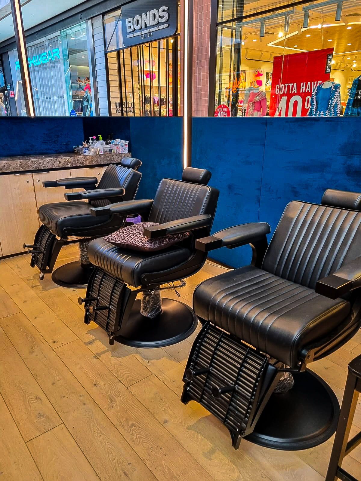 Black leather treatment chairs against the navy velvet wall of the kiosk