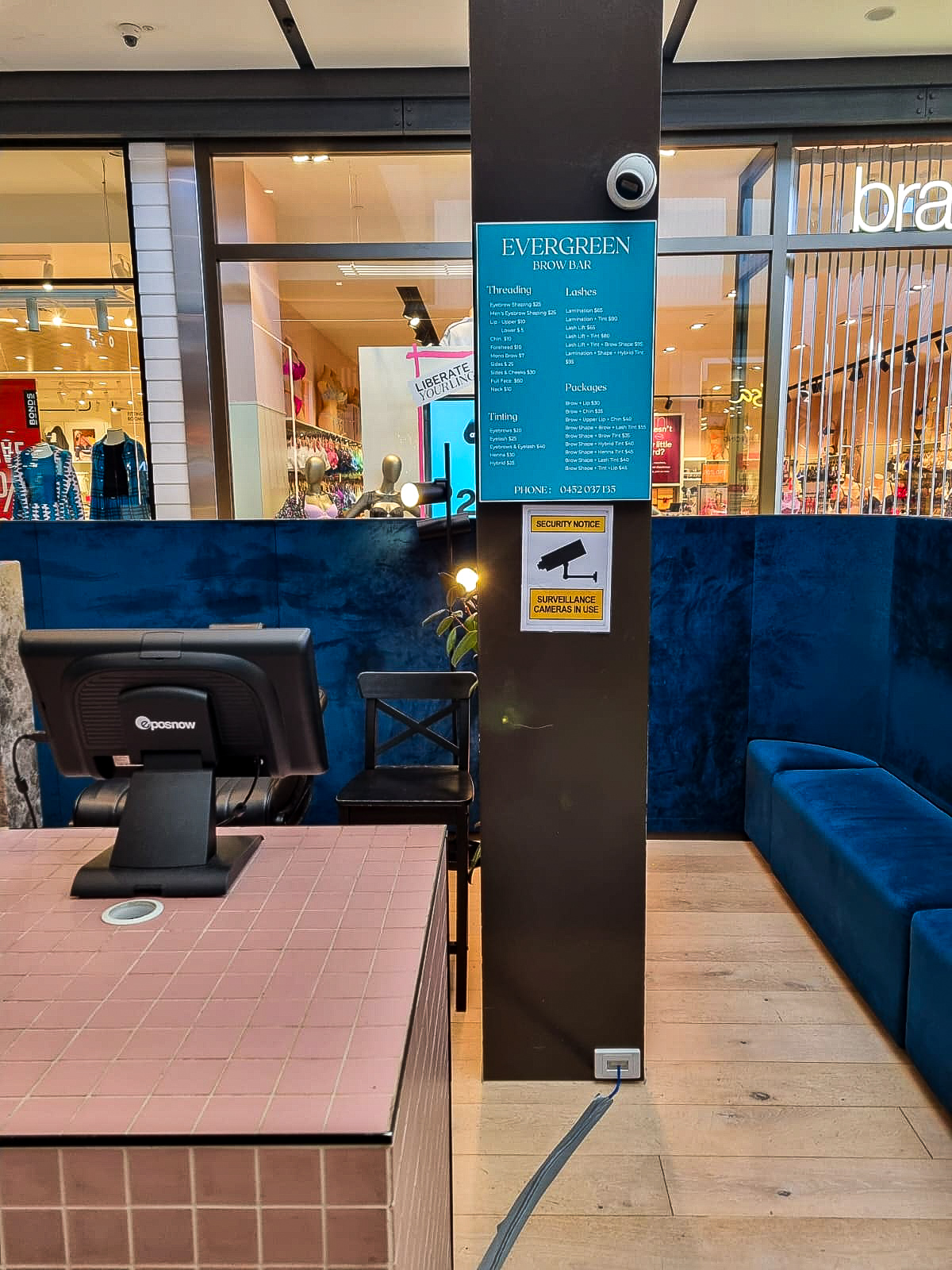 The counter, velvet bench and menu board at Evergreen Brow Bar